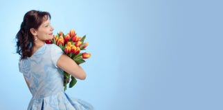 Attraktive Frau im blauen Kleid mit einem Blumenstrauß von roten und gelben Tulpen stockfotos Attraktive Frau im blauen Kleid mit einem Blumenstrauß von roten und gelben Tulpen stockfotos