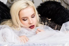 Attraktive sinnliche junge sexy Frau, die schwarze Wäsche und schwarzen die Flügel genießen auf einem Bett trägt stockbild Attraktive sinnliche junge sexy Frau, die schwarze Wäsche und schwarzen die Flügel genießen auf einem Bett trägt stockbild