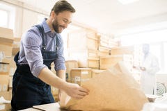 Attrezzatura per imballaggio sorridente del lavoratore del magazzino immagini stock Attrezzatura per imballaggio sorridente del lavoratore del magazzino immagini stock