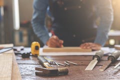 attrezzatura sullo scrittorio di legno con l'uomo che lavora nel fondo dell'officina fotografia stock libera da diritti attrezzatura sullo scrittorio di legno con l'uomo che lavora nel fondo dell'officina fotografia stock libera da diritti