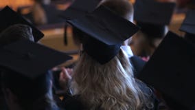 Aufgeregte blonde Frau in der schwarzen Rede des Kleider- und der Kappeapplaudierenden Lehrers stock video footage Aufgeregte blonde Frau in der schwarzen Rede des Kleider- und der Kappeapplaudierenden Lehrers stock video footage