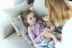 Aufmerksame Mutter sitzt nahe kranker kleiner Tochter stockbild Aufmerksame Mutter sitzt nahe kranker kleiner Tochter stockbild
