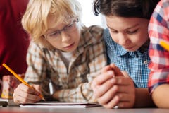 Aufmerksame neugierige Kinder, welche die Aufgabe lesen lizenzfreie stockfotografie Aufmerksame neugierige Kinder, welche die Aufgabe lesen lizenzfreie stockfotografie