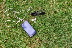 Auricular y gafas de sol del teléfono en la hierba imagenes de archivo Auricular y gafas de sol del teléfono en la hierba imagenes de archivo