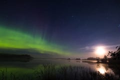 Aurora borealis et pleine lune au-dessus de lac en Finlande Images libres de droits Aurora borealis et pleine lune au-dessus de lac en Finlande Images libres de droits