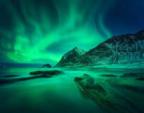 Aurora borealis, schneebedeckter Berg und sandiger Strand mit Steinen lizenzfreie stockfotos Aurora borealis, schneebedeckter Berg und sandiger Strand mit Steinen lizenzfreie stockfotos