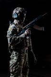 Ausgerüsteter Soldat, der im Profil steht und Automaten oben angehoben hält stockfotografie Ausgerüsteter Soldat, der im Profil steht und Automaten oben angehoben hält stockfotografie