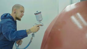 Auto painter spraying red paint on car hood in special booth stock image Auto painter spraying red paint on car hood in special booth stock image