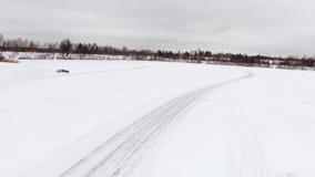 Autoaandrijving door ijzig spoor op sneeuw behandeld meer bij de winter Lucht Mening Sportwagen die op het spoor van het sneeuwra stock video Autoaandrijving door ijzig spoor op sneeuw behandeld meer bij de winter Lucht Mening Sportwagen die op het spoor van het sneeuwra stock video