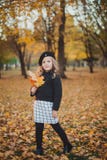 Autunno felice Una bambina in un berretto rosso sta giocando con le foglie cadenti e la risata fotografie stock libere da diritti Autunno felice Una bambina in un berretto rosso sta giocando con le foglie cadenti e la risata fotografie stock libere da diritti