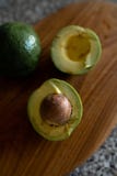 Avocado divisi in due - vista superiore di frutta fresca che ottiene taglio su un bordo fotografie stock Avocado divisi in due - vista superiore di frutta fresca che ottiene taglio su un bordo fotografie stock