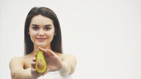 Avocado dla zdrowego ciała Piękna młoda dziewczyna trzyma połówkę avocado w ona i pokazuje na kamerze ręki Podczas to zbiory Avocado dla zdrowego ciała Piękna młoda dziewczyna trzyma połówkę avocado w ona i pokazuje na kamerze ręki Podczas to zbiory