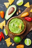Avocado guacamole met ingrediëntenpeper, kalk en nachos op de zwarte mening van de lijstbovenkant Traditioneel Mexicaans Voedsel Royalty-vrije Stock Afbeelding Avocado guacamole met ingrediëntenpeper, kalk en nachos op de zwarte mening van de lijstbovenkant Traditioneel Mexicaans Voedsel Royalty-vrije Stock Afbeelding