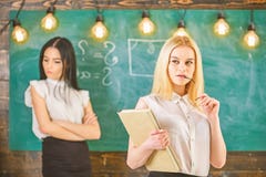 Avund- och konkurrensbegrepp Flicka som ?r svartsjuk av framg?ng av klasskompisen i klassrumet, svart tavla p? bakgrund Kvinna me royaltyfri bild Avund- och konkurrensbegrepp Flicka som ?r svartsjuk av framg?ng av klasskompisen i klassrumet, svart tavla p? bakgrund Kvinna me royaltyfri bild