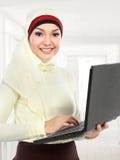 Aziatische jonge moslimvrouw in hoofdsjaal die laptop met behulp van Stock Foto's Aziatische jonge moslimvrouw in hoofdsjaal die laptop met behulp van Stock Foto's
