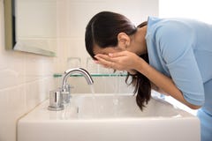 Aziatische vrouw die haar gezicht op de gootsteen wassen stock fotografie Aziatische vrouw die haar gezicht op de gootsteen wassen stock fotografie