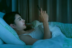 Aziatische vrouw op bed laat bij nacht die gebruikend mobiele telefoonband texting royalty-vrije stock fotografie Aziatische vrouw op bed laat bij nacht die gebruikend mobiele telefoonband texting royalty-vrije stock fotografie