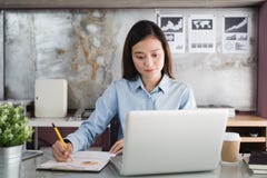 Azjatyckiego kobiety mienia żółty ołówek w ręce i używać laptopie, Żeński działanie w biurowym biurku zdjęcia stock Azjatyckiego kobiety mienia żółty ołówek w ręce i używać laptopie, Żeński działanie w biurowym biurku zdjęcia stock