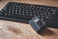Ação-câmera no fundo de um teclado preto em uma tabela de madeira imagem de stock Ação-câmera no fundo de um teclado preto em uma tabela de madeira imagem de stock