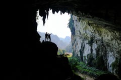 Ba Be Lakes / Vietnam, 03/11/2017: Silhouettes of two people standing in a rocky outcrop inside a giant cave in the North royalty free stock photos Ba Be Lakes / Vietnam, 03/11/2017: Silhouettes of two people standing in a rocky outcrop inside a giant cave in the North royalty free stock photos