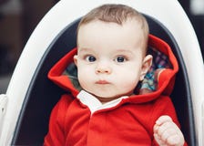 Baby boy with dark black eyes sitting in high chair Stock Photos Baby boy with dark black eyes sitting in high chair Stock Photos