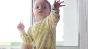 Baby, das an den wellenartig bewegenden Händen des Fensters sitzt stock footage Baby, das an den wellenartig bewegenden Händen des Fensters sitzt stock footage