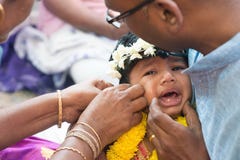 Baby, das in der piercing Zeremonie des Hinduohrs schreit lizenzfreie stockbilder Baby, das in der piercing Zeremonie des Hinduohrs schreit lizenzfreie stockbilder