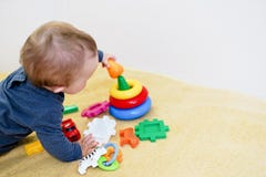 Baby die en met kleurrijk speelgoed thuis smilling spelen kindachtergrond met exemplaarruimte Vroege ontwikkeling voor kinderen royalty-vrije stock fotografie Baby die en met kleurrijk speelgoed thuis smilling spelen kindachtergrond met exemplaarruimte Vroege ontwikkeling voor kinderen royalty-vrije stock fotografie