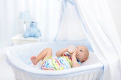 Baby drinking milk. Boy with formula bottle in bed Stock Images Baby drinking milk. Boy with formula bottle in bed Stock Images