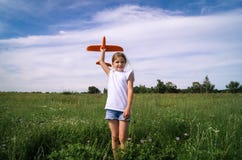 A baby girl is launching a toy airframe glider in a field against a blue sky background with clouds. Royalty Free Stock Images A baby girl is launching a toy airframe glider in a field against a blue sky background with clouds. Royalty Free Stock Images