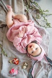 Baby som ligger på linnefilten och bär en hatt i form av en påskkanin med äggpilfilialer och påskpajen royaltyfri foto Baby som ligger på linnefilten och bär en hatt i form av en påskkanin med äggpilfilialer och påskpajen royaltyfri foto