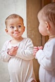 Baby standing against the mirror Royalty Free Stock Photography Baby standing against the mirror Royalty Free Stock Photography