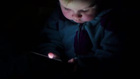 Babys face illuminated by smartphone glow, 4K
