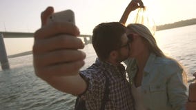 Baciare le giovani coppie prende la fotografia contro il sole brillantemente brillante ed il fiume brillante Baciare le giovani coppie prende la fotografia contro il sole brillantemente brillante ed il fiume brillante