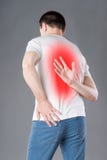 Back pain, man suffering from backache on gray background stock image Back pain, man suffering from backache on gray background stock image