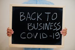 Back to business covid-19. Coronavirus concept. Boy hold inscription on the board