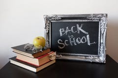 Back to school, chalk in a vintage frame. Text on chalkboard and a stack of textbooks royalty free stock image Back to school, chalk in a vintage frame. Text on chalkboard and a stack of textbooks royalty free stock image