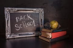 Back to school, text on chalkboard and a stack of textbooks. Textured vintage frame on a dark textured background. royalty free stock photo Back to school, text on chalkboard and a stack of textbooks. Textured vintage frame on a dark textured background. royalty free stock photo