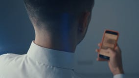 Back view Man at office using Smartphone, Doing Swiping, Scrolling Gestures. Businessman Using Mobile Phone, Internet stock video footage Back view Man at office using Smartphone, Doing Swiping, Scrolling Gestures. Businessman Using Mobile Phone, Internet stock video footage