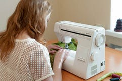 Eamstress sitting at white sewing machine and working near window royalty free stock images Eamstress sitting at white sewing machine and working near window royalty free stock images