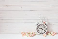 Background with white alarm clock and small pink roses on white Stock Photography Background with white alarm clock and small pink roses on white Stock Photography
