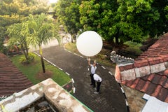 BADUNG/BALI-APRIL 10 2019: Obserwator uwalnia dużego bielu radia sonde balon mierzyć przy Ngurah Rai Meteorologiczną stacją obraz stock BADUNG/BALI-APRIL 10 2019: Obserwator uwalnia dużego bielu radia sonde balon mierzyć przy Ngurah Rai Meteorologiczną stacją obraz stock
