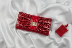 Bag of lacquered leather and red perfume lying on white silk. Handbag for women and bottle of scent, top view. Stock Photos Bag of lacquered leather and red perfume lying on white silk. Handbag for women and bottle of scent, top view. Stock Photos