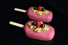 Bagas e gelado cor-de-rosa do gelato do pistache na vara com framboesas, os corintos pretos e a esponja do pistache imagens de stock royalty free Bagas e gelado cor-de-rosa do gelato do pistache na vara com framboesas, os corintos pretos e a esponja do pistache imagens de stock royalty free