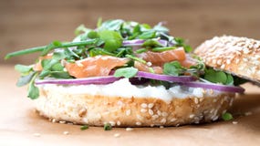 Bagel sandwich with creame cheese, salmon,onion,tomato,greens,ch. Ives close-up on a wooden background. Delicious bagel, golden bake color, soft inside, crispy Royalty Free Stock Photos