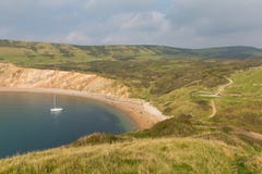 Baia di Worbarrow ad est della baia di Lulworth e vicino a Tyneham sulla costa Inghilterra Regno Unito di Dorset con l'yacht fotografia stock Baia di Worbarrow ad est della baia di Lulworth e vicino a Tyneham sulla costa Inghilterra Regno Unito di Dorset con l'yacht fotografia stock