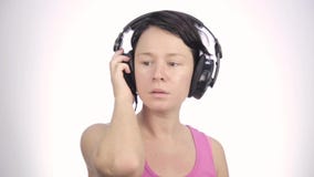 Baile hermoso de la mujer en auriculares mientras que escucha una música en un fondo ligero almacen de video Baile hermoso de la mujer en auriculares mientras que escucha una música en un fondo ligero almacen de video