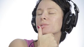 Baile hermoso de la mujer en auriculares mientras que escucha una música en un fondo ligero almacen de metraje de vídeo Baile hermoso de la mujer en auriculares mientras que escucha una música en un fondo ligero almacen de metraje de vídeo