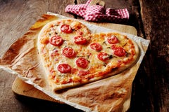 Baked hjärta-formade pizza som överträffades med tomatskivor royaltyfri foto Baked hjärta-formade pizza som överträffades med tomatskivor royaltyfri foto