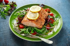 Baked salmon steak with tomato, onion, mix of green leaves salad in a plate. healthy food Royalty Free Stock Photo Baked salmon steak with tomato, onion, mix of green leaves salad in a plate. healthy food Royalty Free Stock Photo
